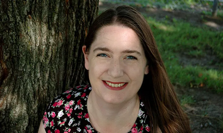 Portrait of Anita Descheneau sitting outdoors beside a tree.