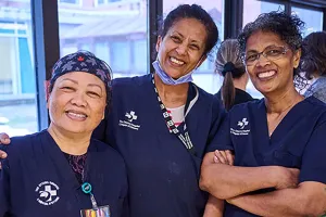 Three hospital employees wearing blue scrubs posing for a photo at Staff Winterfest.
