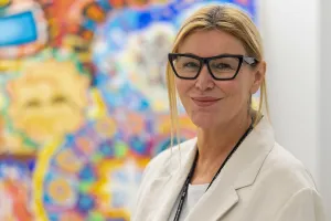 La Dre Mary Marquardt debout devant des créations d’art thérapeutique colorées faites par des clients du programme On avance. 
