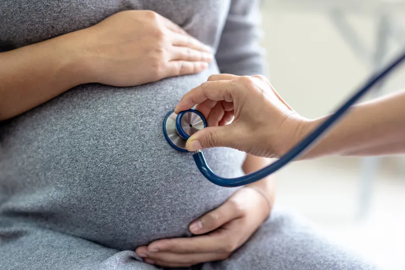 Une professionnelle de la santé examine le ventre d’une patiente enceinte à l’aide d’un stéthoscope.