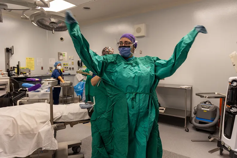 Jessica Richards, infirmière autorisée, met une blouse chirurgicale réutilisable de couleur vert clair dans une salle d’opération du Campus Général.