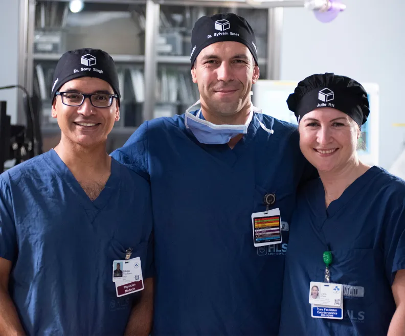 Three TOH staff members in surgical scrubs stand together in a hospital environment. 