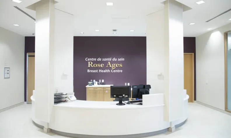 Reception desk at the Rose Ages Breast Health Centre with a purple accent wall and signage in the background.