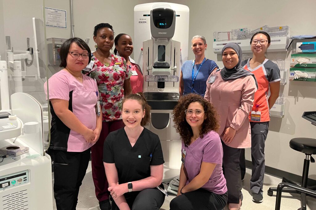 The clinic’s medical radiation technologists pose with a mammogram machine.