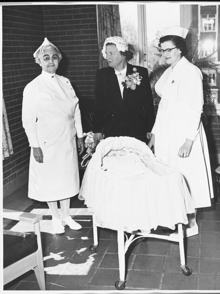 La princesse Juliana des Pays-Bas accompagnée de deux infirmières à l’Hôpital Civic d’Ottawa. Elles se trouvent autour du lit de bébé qui a servi après la naissance de la princesse Margriet, en janvier 1943.