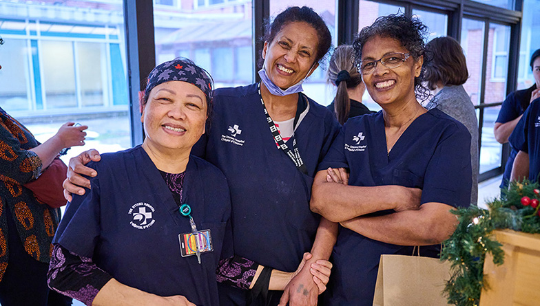 Three hospital employees wearing blue scrubs posing for a photo at Staff Winterfest.